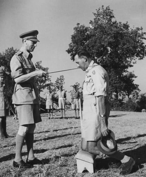 Lieutenant General Sir Oliver Leese of the British Army receives a knighthood from King George VI, during the King's visit with the Eighth Army in Italy in 1944.