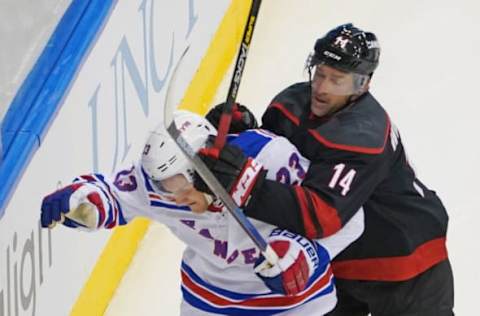 Justin Williams #14 of the Carolina Hurricanes checks Adam Fox (Photo by Andre Ringuette/Getty Images)