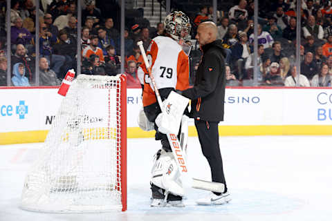 Carter Hart speaks with a Philadelphia Flyers medical trainer before exiting their latest game against the Buffalo Sabres. (Photo by Tim Nwachukwu/Getty Images)