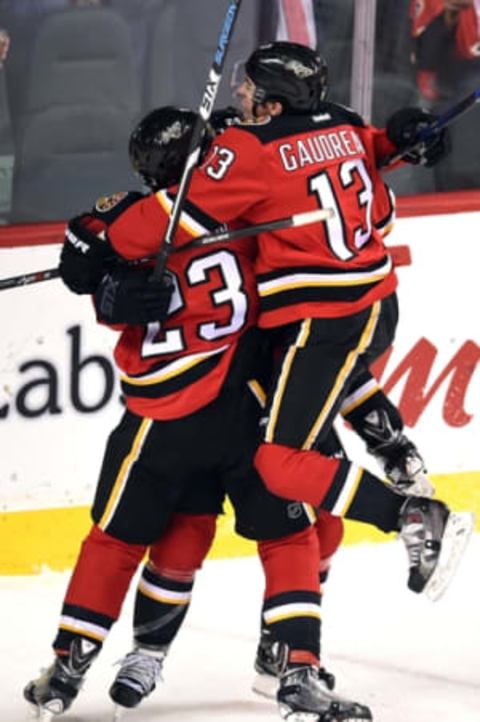 Dec 4, 2015; Calgary, Alberta, CAN; Calgary Flames left wing Johnny Gaudreau (13) jumps on center Jiri Hudler (24) and center Sean Monahan (23) to celebrate Hudler