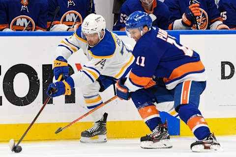 Dec 30, 2021; Elmont, New York, USA; Buffalo Sabres center Rasmus Asplund (74) and New York Islanders left wing Zach Parise (11) battle for the puck during the first period at UBS Arena. Mandatory Credit: Dennis Schneidler-USA TODAY Sports