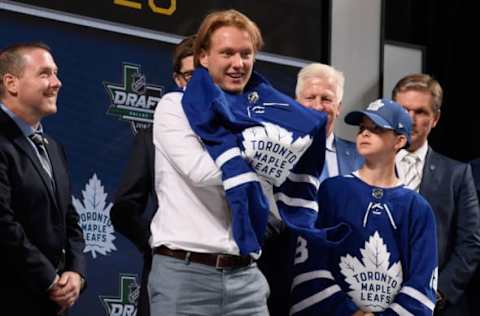 DALLAS, TX – JUNE 22: Rasmus Sandin puts on a Toronto Maple Leafs jersey after being selected twenty-ninth overall by the Toronto Maple Leafs during the first round of the 2018 NHL Draft at American Airlines Center on June 22, 2018 in Dallas, Texas. (Photo by Brian Babineau/NHLI via Getty Images)