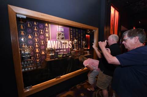 LAS VEGAS, NV – JUNE 17: Guests take photos of (L-R) the Conn Smythe Trophy, the Frank J. Selke Trophy, the Presidents’ Trophy, the Lady Byng Memorial Trophy and the Calder Memorial Trophy on display in a glass case at the Hard Rock Hotel & Casino in advance of the 2018 NHL Awards on June 17, 2018 in Las Vegas. Nevada. The 2018 NHL Awards will be held at the Hard Rock on June 20. (Photo by Ethan Miller/Getty Images)