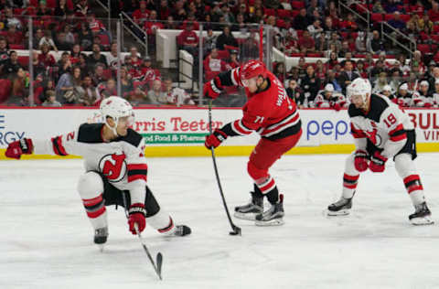 RALEIGH, NC – NOVEMBER 18: Carolina Hurricanes Center Lucas Wallmark (71) shoots the puck between New Jersey Devils Defenceman Ben Lovejoy (12) and New Jersey Devils Center Travis Zajac (19) during a game between the Carolina Hurricanes and the New Jersey Devils at the PNC Arena in Raleigh, NC on November 18, 2018. (Photo by Greg Thompson/Icon Sportswire via Getty Images)