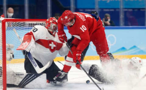 Feb 9, 2022; Beijing, China; Anton Reto Berra of Switzerland and Raphael Diaz of Switzerland in action with Dmitrii Voronkov of the Russian Olympic Committee in MenÕs Ice Hockey Group B play during the Beijing 2022 Olympic Winter Games at National Indoor Stadium. Mandatory Credit: David W Cerny/Reuters-USA TODAY Sports