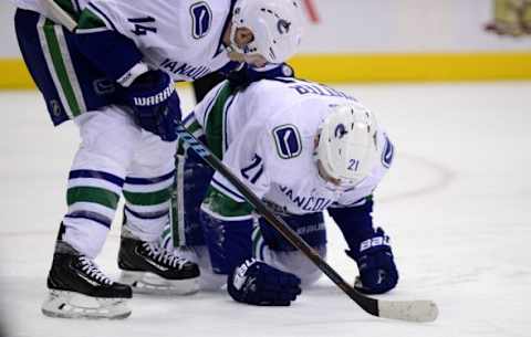 Feb 9, 2016; Denver, CO, USA; Vancouver Canucks left wing Alex Burrows (14) comforts an injured center Brandon Sutter (21) in the second period against the Colorado Avalanche at the Pepsi Center. Mandatory Credit: Ron Chenoy-USA TODAY Sports