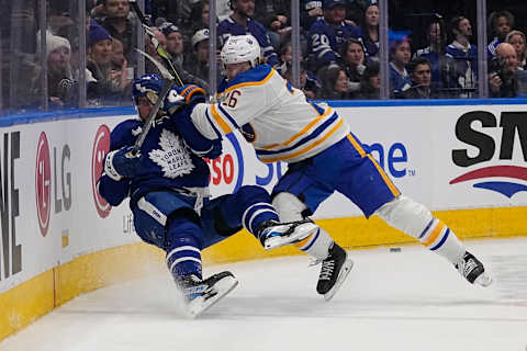 Mar 13, 2023; Toronto, Ontario, CAN; Buffalo Sabres defenseman Rasmus Dahlin (26) hits Toronto Maple Leafs forward Auston Matthews (34) into the boards during the first period at Scotiabank Arena. Mandatory Credit: John E. Sokolowski-USA TODAY Sports