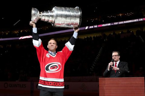 RALEIGH, NC – FEBRUARY 13: Brett Hedican, 2005-2006 Carolina Hurricanes Stanley Cup Champion team member and analyst for the San Jose Sharks, raises the Stanley Cup at the pregame 10th Anniversary Celebration as announcer John Forslund looks on prior to an NHL game against the New York Islanders at PNC Arena on February 13, 2016 in Raleigh, North Carolina. (Photo by Gregg Forwerck/NHLI via Getty Images)