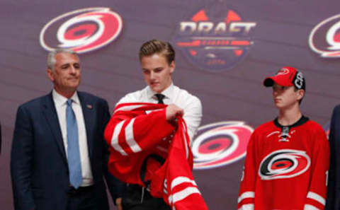 Jun 24, 2016; Buffalo, NY, USA; Jake Bean puts on a team jersey after being selected as the number thirteen overall draft pick by the Carolina Hurricanes in the first round of the 2016 NHL Draft at the First Niagra Center. Mandatory Credit: Timothy T. Ludwig-USA TODAY Sports