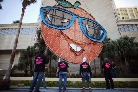 Workers watch as the Big Orange, a New Year's time ball, is prepared to be raised onto the side of the Hotel InterContinental