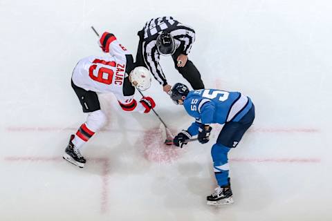 WINNIPEG, MB – NOVEMBER 11: Travis Zajac #19 of the New Jersey Devils takes a second period face-off against Mark Scheifele #55 of the Winnipeg Jets at the Bell MTS Place on November 11, 2018 in Winnipeg, Manitoba, Canada. (Photo by Jonathan Kozub/NHLI via Getty Images)