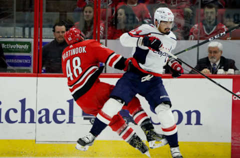 RALEIGH, NC – DECEMBER 28: Jordan Martinook #48 of the Carolina Hurricanes and Jonas Siegenthaler #34 of the Washington Capitals collide along the boards during an NHL game on December 28, 2019 at PNC Arena in Raleigh, North Carolina. (Photo by Gregg Forwerck/NHLI via Getty Images)