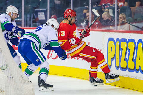 Oct 1, 2021; Calgary, Alberta, CAN; Calgary Flames left wing Johnny Gaudreau (13) and Vancouver Canucks defenseman Brad Hunt (77) battle for the puck during the first period at Scotiabank Saddledome. Mandatory Credit: Sergei Belski-USA TODAY Sports