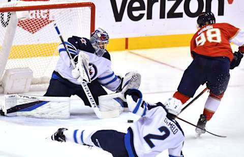 Apr 15, 2022; Sunrise, Florida, USA; Florida Panthers center Maxim Mamin (98) slides the puck under Winnipeg Jets goaltender Eric Comrie (1) for a goal during the third period at FLA Live Arena. Mandatory Credit: Jim Rassol-USA TODAY Sports