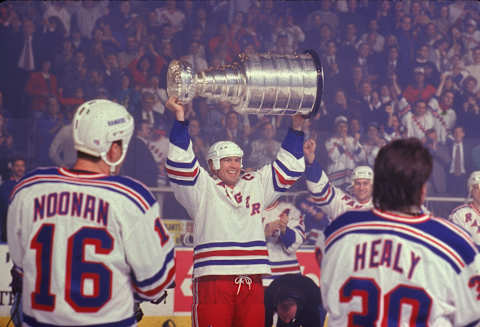 Canadian professional hockey player Mark Messier of the New York Rangers hoists the Stanley Cup championship award trophy over his head as teammates American Brian Noonan (#16) and Canadian Glenn Healy (#30) look on during the opening night of the 1995 NHL season, Madison Square Garden, New York, January 20, 1995. The 1994-95 Season was shortened to the 1995 Season because of a lockout in Fall 1994. The Rangers opening game was against the Buffalo Sabres and they lost 2-1. (Photo by Bruce Bennett Studios/Getty Images)