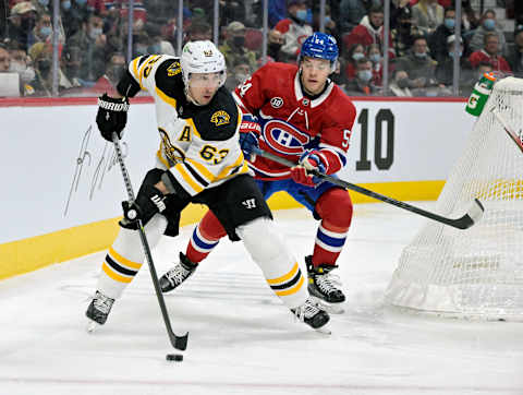 Apr 24, 2022; Montreal, Quebec, CAN; Boston Bruins forward Brad Marchand (63) plays the puck, and Montreal Canadiens defenseman Jordan Harris (54) defends during the first period at the Bell Centre. Mandatory Credit: Eric Bolte-USA TODAY Sports