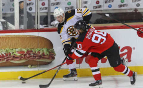 Jan 14, 2021; Newark, New Jersey, USA; Boston Bruins center Charlie Coyle (13) and New Jersey Devils center Jesper Boqvist (90) battle for the puck during the second period at Prudential Center. Mandatory Credit: Ed Mulholland-USA TODAY Sports