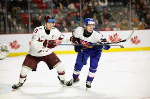 MONCTON, NB – DECEMBER 30: Gustavs Ozolins #9 of Team Latvia checks Adam Sykora #14 of Team Slovakia during the first period during the 2023 IIHF World Junior Championship game at Avenir Centre on December 30, 2022, in Moncton, Canada. (Photo by Dale Preston/Getty Images)