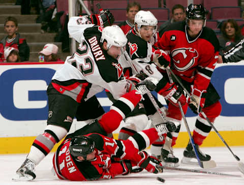 EAST RUTHERFORD, NJ – OCTOBER 28: John Madden #11 and Paul Martin #7 of the New Jersey Devils battle for the puck with Chris Drury #23 and Daniel Briere #48 of the Buffalo Sabres at Continental Airlines Arena on October 28, 2005 in East Rutherford, New Jersey. (Photo by Ezra Shaw/Getty Images)