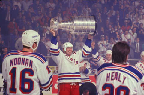 Canadian professional hockey player Mark Messier of the New York Rangers hoists the Stanley Cup championship award trophy over his head as teammates American Brian Noonan (#16) and Canadian Glenn Healy (#30) look on during the opening night of the 1995 NHL season, Madison Square Garden, New York, January 20, 1995. The 1994-95 Season was shortened to the 1995 Season because of a lockout in Fall 1994. The Rangers opening game was against the Buffalo Sabres and they lost 2-1. (Photo by Bruce Bennett Studios/Getty Images)