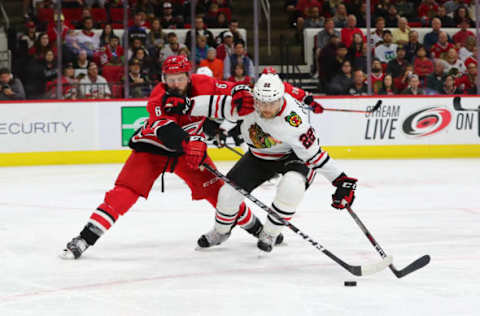 RALEIGH, NC – OCTOBER 26: Chicago Blackhawks center Ryan Carpenter (22) and Carolina Hurricanes defenseman Joel Edmundson (6) fight for the puck during the 3rd period of the Carolina Hurricanes game versus the Chicago Blackhawks on October 26th, 2019 at PNC Arena in Raleigh, NC. (Photo by Jaylynn Nash/Icon Sportswire via Getty Images)