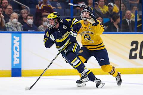 Apr 6, 2023; Tampa, Florida, USA; Michigan forward Gavin Brindley (4) and Quinnipiac defenseman Zach Metsa (23) battle fro the puck during the first period in the semifinals of the 2023 Frozen Four college ice hockey tournament at Amalie Arena. Mandatory Credit: Nathan Ray Seebeck-USA TODAY Sports