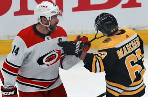 BOSTON – MAY 12: Carolina Hurricanes’ Justin Williams (14) has the Bruins’ Brad Marchand (63) by the chin strap during the second period. The Boston Bruins host the Carolina Hurricanes in Game 2 of the NHL Eastern Conference Finals on May 12, 2019. (Photo by Jim Davis/The Boston Globe via Getty Images)