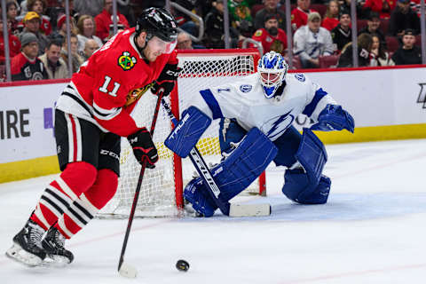 Jan 3, 2023; Chicago, Illinois, USA; Chicago Blackhawks right wing Taylor Raddysh (11) skates with the puck as Tampa Bay Lightning goaltender Brian Elliott (1) defends his goal during the first period at the United Center. Mandatory Credit: Daniel Bartel-USA TODAY Sports