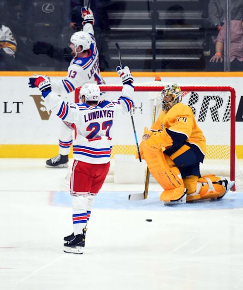 Oct 21, 2021; Nashville, Tennessee, USA; New York Rangers left wing Alexis Lafreniere (13) and New York Rangers defenseman Nils Lundkvist (27) celebrate after a goal past Nashville Predators goaltender Juuse Saros (74) during the first period at Bridgestone Arena. Mandatory Credit: Christopher Hanewinckel-USA TODAY Sports