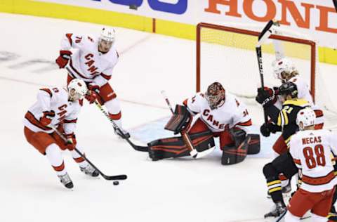 Warren Foegele #13, Brady Skjei #76 and Petr Mrazek #34 of the Carolina Hurricanes defend against the Boston Bruins  (Photo by Elsa/Getty Images)