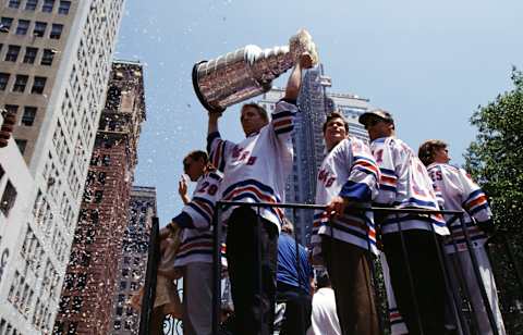 Brian Leetch #2 of the New York Rangers holds the Stanley Cup Trophy as his teammates Mark Messier #11 and goalie Mike Richter #35 ride along with him  (Photo by Bruce Bennett Studios via Getty Images Studios/Getty Images)