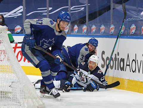 TORONTO, ON – MARCH 9: Trevor Lewis #23 of the Winnipeg Jets is knocked down by Justin Holl #3 of the Toronto Maple Leafs while teammate Pierre Engvall #47   (Photo by Claus Andersen/Getty Images)