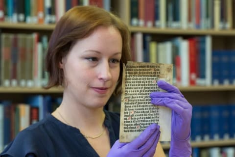 Librarian Erika Delbecque holds up the Caxton leaf.