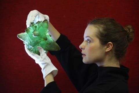 A Bonhams auction house employee holds a Kryptonite prop crystal from the film Superman III.