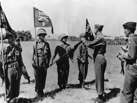 General Mark Clark fastens citation streamers on 100th battalion flags for outstanding performance of duties in the Mediterranean theater.