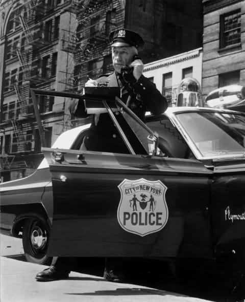 A New York City police officer takes an emergency call from his car in the 1960s