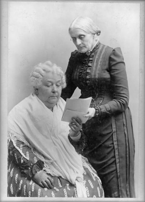 Elizabeth Stanton sits as Susan B Anthony stands nearby.