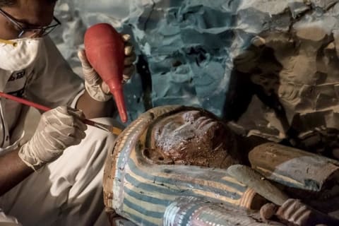 An Egyptian archaeologist restores an ornately decorated wood sarcophagus discovered in the tomb of Amenemhat, a royal goldsmith.