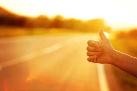 A close up of a man's hand as he hitchhikes.