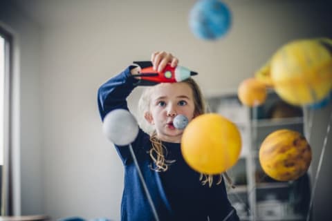 A little girl plays with a toy rocketship in a space system.