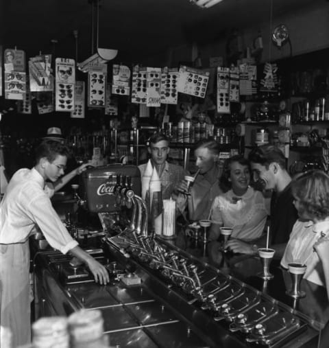 A soda jerk serves sweet drinks at a drugstore's soda fountain in 1950.