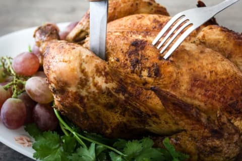 A knife and fork in a turkey that's about to be carved.