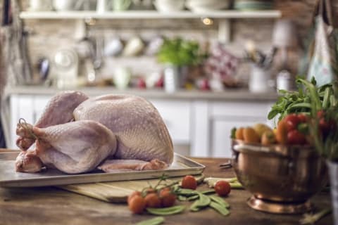 A raw turkey sitting on a cutting board.