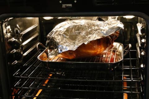 A turkey in the oven covered with foil.