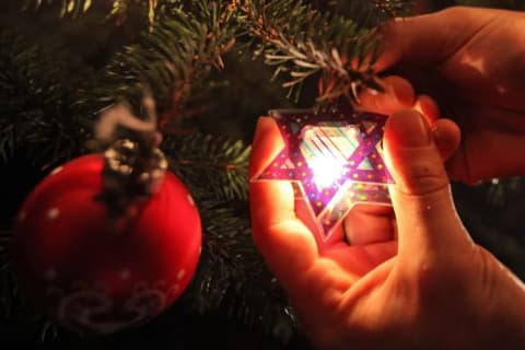 Hanging a Star of David on a Christmas tree.