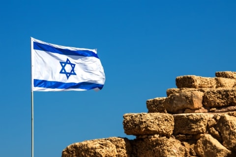 Israeli flag flying near a rock wall