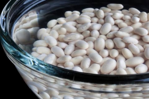 White beans soaking in a glass bowl