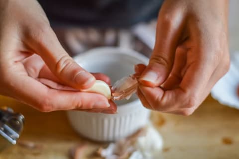 Hands peeling a clove of garlic