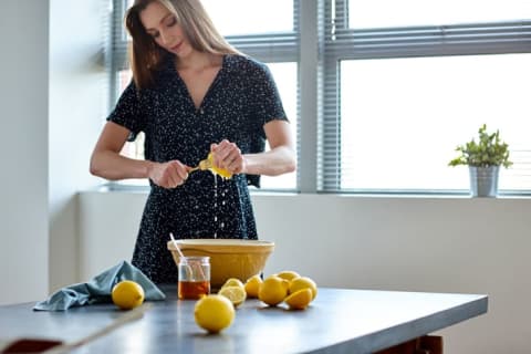 A woman squeezes lemon juice into a bowl.