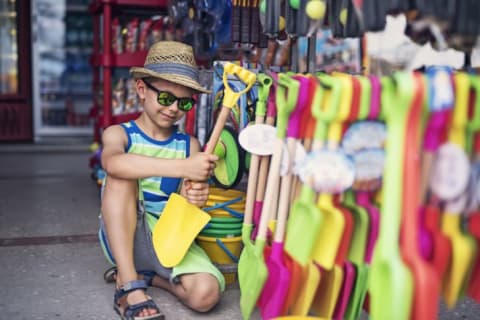 Little boy shops for a beach shovel